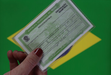 Brazil voter registration card in a woman’s hand with the Brazil flag in the background 
