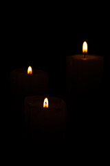 Candles, beautiful candles positioned on dark surface, black background, selective focus.