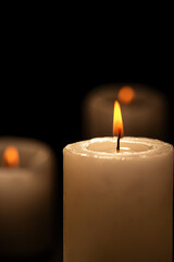 Candles, beautiful candles positioned on dark surface, black background, selective focus.