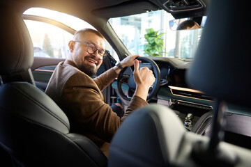 Man smiles while sitting behind the wheel of a car