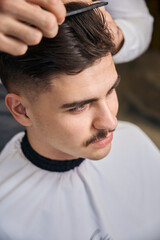 Man hairstylist serving client with mustache