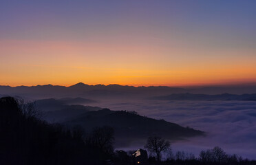 Un mare di nuvole bianche  e di nebbia riempie le valli sotto le montagneal tramonto 