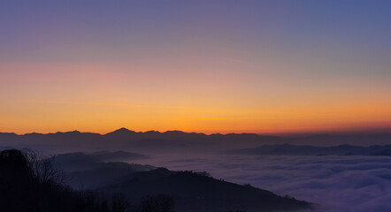 Un mare di nuvole bianche  e di nebbia riempie le valli sotto le montagneal tramonto  - obrazy, fototapety, plakaty