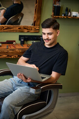 Barber communicating online via laptop