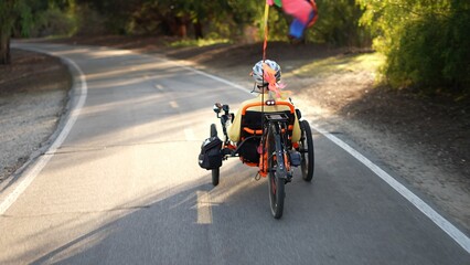 Rear view of elderly senior woman riding a recumbent electric bike on a bike path in Southern...