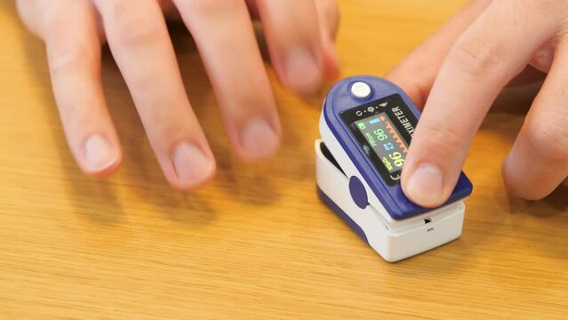 Human hand pulse oximeter used to measure pulse rate and oxygen levels close up. Male hand measures heart rate with heart rate monitor top view, Medical concept