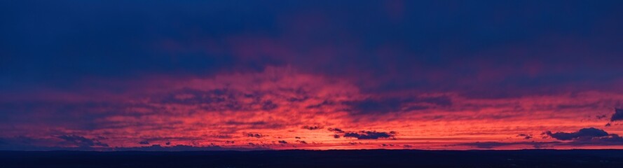 Ideal for sky replacement projects: panoramic aerial shot of a  red and orange illuminated clouds of dark blue evening sky just after sunset.
