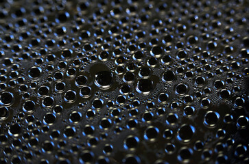 Large drops of water on a dark surface close-up