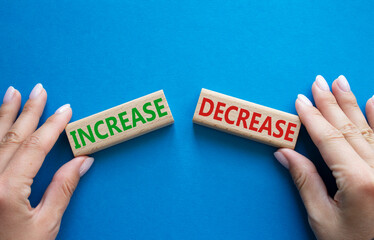 Increase or Decrease symbol. Concept word Increase or Decrease on wooden blocks. Businessman hand. Beautiful blue background. Business and Increase or Decrease concept. Copy space