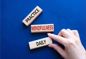 Practice Mindfulness Daily symbol. Concept words Practice Mindfulness Daily on wooden blocks. Businessman hand. Beautiful deep blue background. Medical and Psychology concept. Copy space.