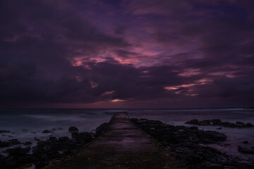 Obraz premium Long exposure view of sunrise from a pier at La Cambuse beach which is located in the south of Mauritius island 
