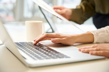 Unrecognizable clothing designer and assistant working together