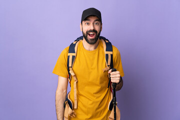Caucasian handsome man with backpack and trekking poles over isolated background with surprise...