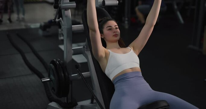 Woman doing exercise for chest on training apparatus at the gym