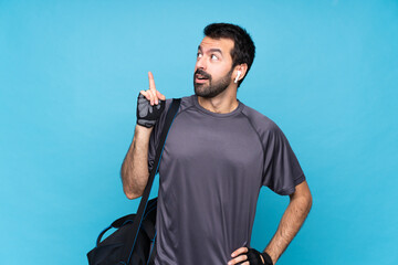 Young sport man with beard over isolated blue background thinking an idea pointing the finger up