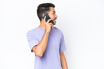 Young handsome man over isolated white background keeping a conversation with the mobile phone with someone