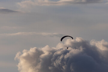 Parachutist moving quickly leaving clouds and blue sky behind