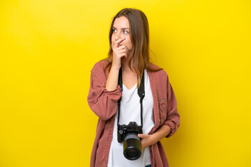 Young photographer caucasian woman isolated on yellow background having doubts and with confuse...