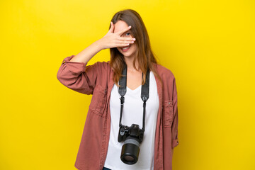 Young photographer caucasian woman isolated on yellow background covering eyes by hands and smiling