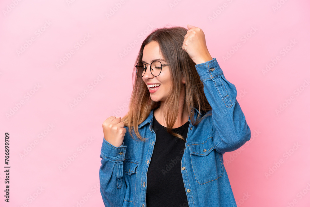 Wall mural Young caucasian woman isolated on pink background celebrating a victory