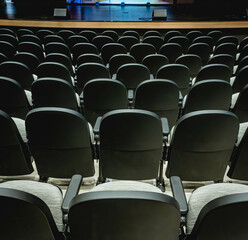 empty seats sit in an auditorium under a spotlight from the stage