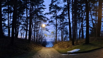 The walking path to the sea between Dunes is illuminated by lantern in the evening