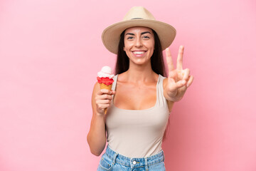 Young caucasian woman with a cornet ice cream isolated on pink background smiling and showing...