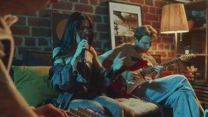 Side footage of Caucasian woman energetically and passionately signing into microphone being accompanied on guitar while rehearsing music in vintage studio