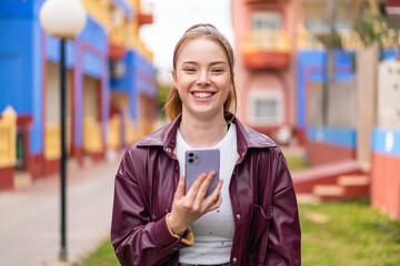 Young pretty girl using mobile phone at outdoors smiling a lot