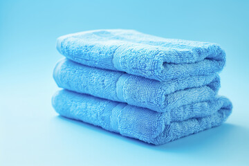 Light blue spa towels pile, bath towels lying in a stack on light blue peaceful background with copy space.