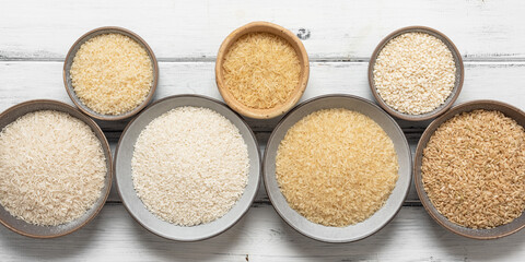 Assortment of various raw rice in bowls, white wooden background. Top view, flat lay. Banner. - 766611357