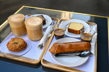 Paris, France. A rich breakfast with typical desserts and cappuccino and coffee. Three-quarter view.