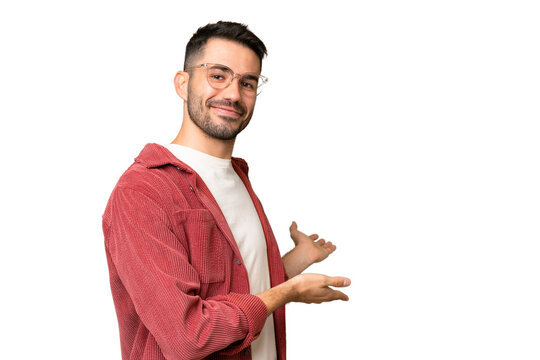 Young handsome caucasian man over isolated chroma key background extending hands to the side for inviting to come