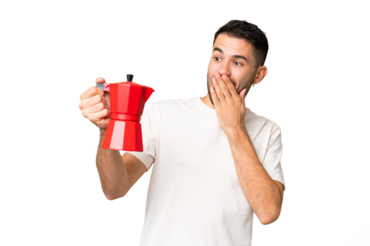 Young caucasian man holding coffee pot over isolated chroma key background with surprise and shocked facial expression