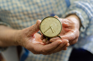 Grandmother holding an old watch in her hands. Concept of old age and quick passage of time
