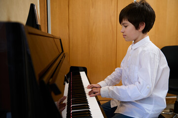 Authentic portrait of handsome boy musician pianist performing classic melody, practicing chord...