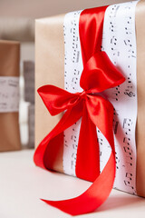 Stylish birthday or christmas gift. A gift packed in paper with notes tied with a red gift ribbon. Festive concept - 766621191