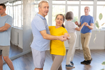 Elderly man and elderly woman dance ballroom dance waltz in studio