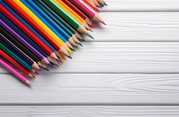 Obraz premium Colored pencils on white wood background with copy space, top view