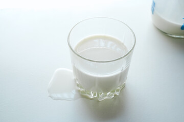 白いテーブルの上のグラスに入った牛乳と牛乳瓶