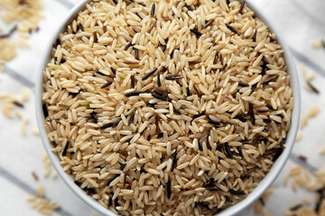 Raw Organic Wild Rice in a Bowl on a white wooden background, top view.