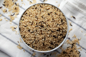 Raw Organic Wild Rice in a Bowl on a white wooden background, top view.