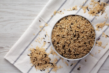 Raw Organic Wild Rice in a Bowl on a white wooden background, top view.
