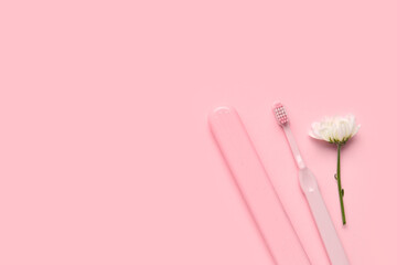 Toothbrush, case and chamomile flower on pink background
