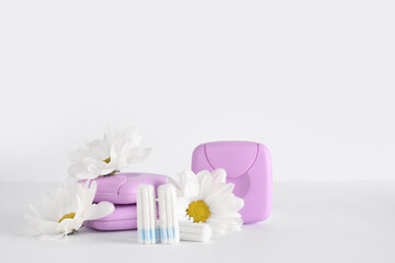 Fototapeta na wymiar Menstrual tampons, storage boxes and chamomile flowers on white background