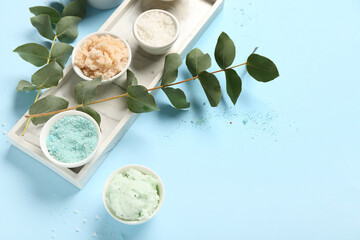 Tray with scrubs, sea salt and eucalyptus on blue background. Body massage concept
