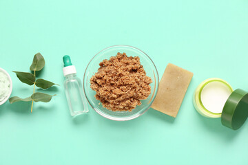 Scrub with cream, cosmetic oil and soap on turquoise background. Body massage concept