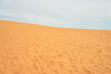Sand dune in the desert with clouds in the background.