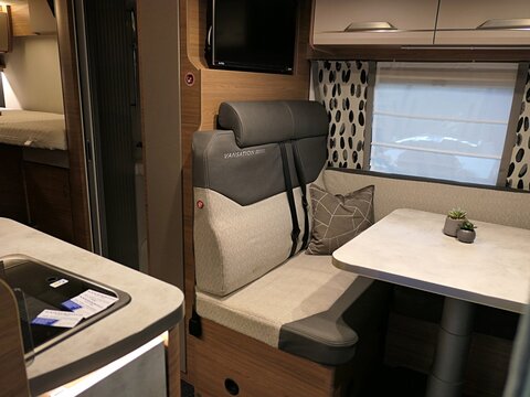 Comfy interior detail of modern german camper van Knaus Van Wave 640 MEG, dining table, seats, windows and part of kitchen sink is visible. Displayed on Caravan Bike Travel expo in Nitra, Slovakia.