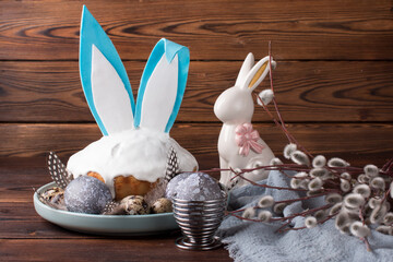 Easter cake on a plate, painted eggs with willow branches and an Easter bunny. A greeting card
